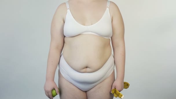 Mujer regordeta mostrando manzana y cinta adhesiva delante de la cámara, estilo de vida saludable, dieta — Vídeo de stock