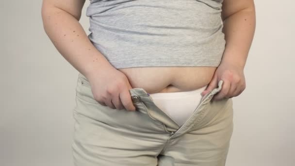 Mujer con sobrepeso tratando de abotonar los pantalones antes de la cámara, la obesidad, además de tamaño — Vídeos de Stock