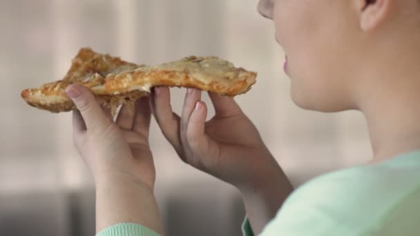 Corpulenta hembra comiendo rebanada de pizza y disfrutando del sabor, sobrepeso, comida chatarra — Vídeo de stock