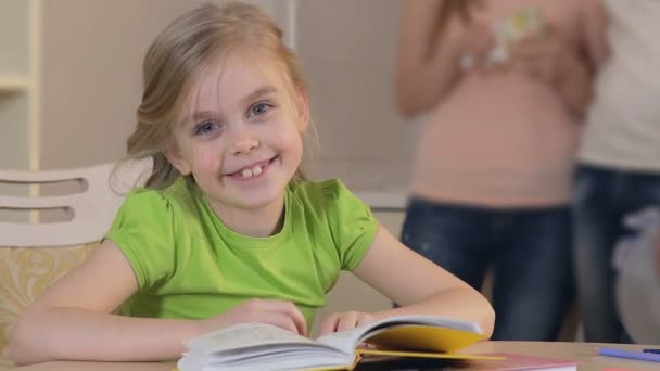 Pretty little girl sitting at the table and looking into camera, happy family — Stock Video