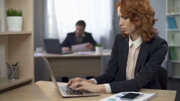 Empleada en traje sentada en el escritorio y escribiendo en la computadora, trabajo de oficina — Vídeos de Stock