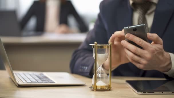 Empresário usando telefone celular, tempo de medição de ampulheta, procrastinação — Vídeo de Stock