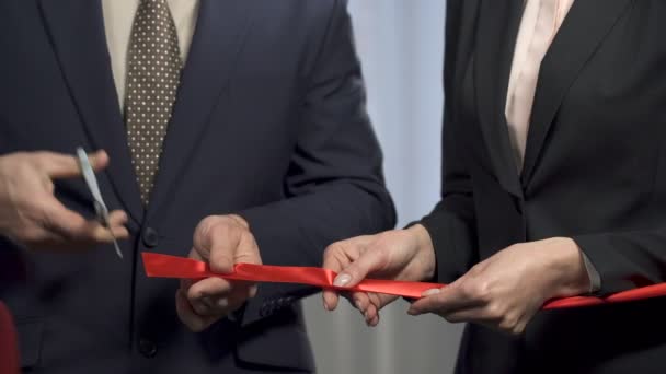 Empresário cortando fita vermelha com tesoura, apertando as mãos com o parceiro, lançamento — Vídeo de Stock