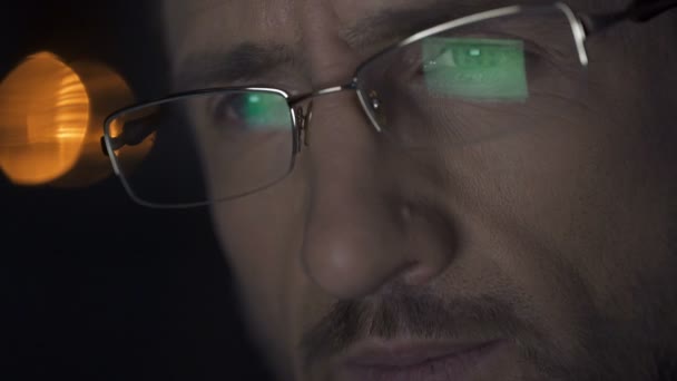 Чоловік працює на ноутбуці вночі, екран ноутбука з файлами, відображеними в окулярах — стокове відео