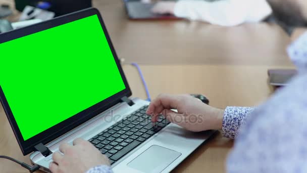 Мужчина работает на ноутбуке с зеленым экраном за рабочим столом в офисе — стоковое видео