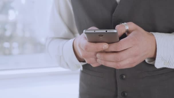 Розумно одягнений чоловік тримає смартфон в руках, прокручуючи стрічку новин соціальних мереж — стокове відео