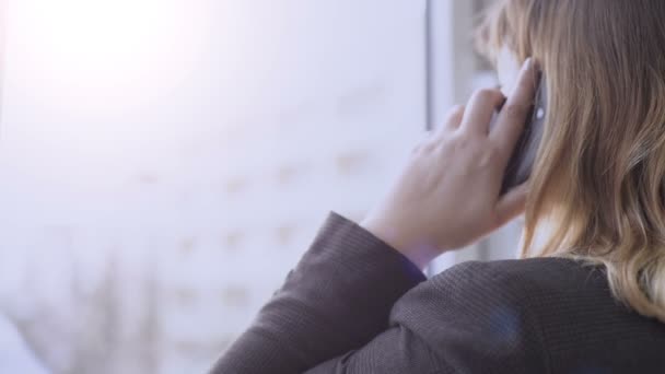 Kobieta poszukuje okno podczas rozmowy przez telefon komórkowy — Wideo stockowe