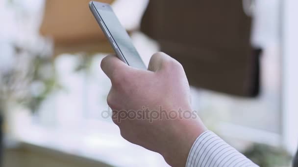 Mão de homem rolando páginas da web no smartphone, lendo notícias de negócios online — Vídeo de Stock