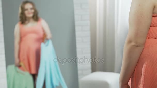 Дівчина-підліток з додатковою вагою підбирає нове вбрання перед дзеркалом на повну висоту — стокове відео