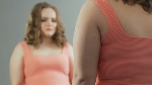 Mujer con peso extra mirando su reflejo en el espejo con autoaversión — Vídeo de stock