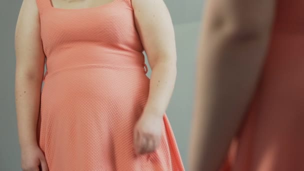 Overweight female standing in front of mirror, touching fat stomach and sobbing — Stock Video