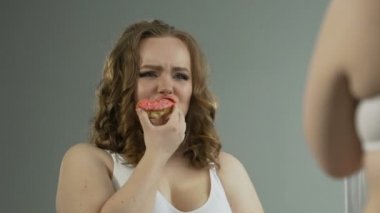 Umutsuzluk içinde donut yemek ayna, vücutta bakarak depresif kilolu kız