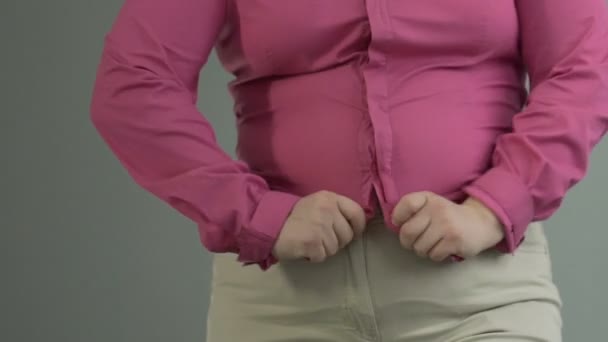 Oversized meisje hopeloos probeert te knop kleine shirt, gewicht controle probleem — Stockvideo