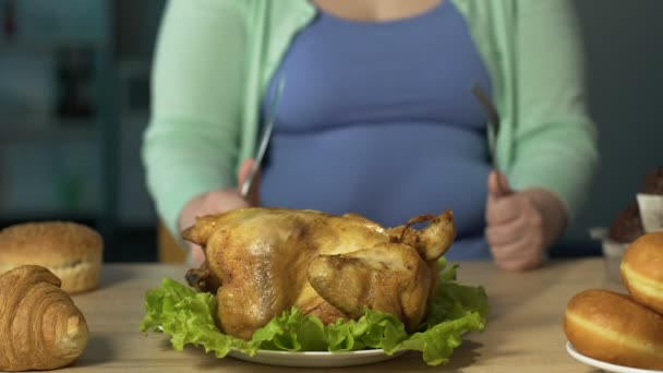 Senhora gorda afiar faca contra garfo, preparando-se para comer frango assado grande — Vídeo de Stock