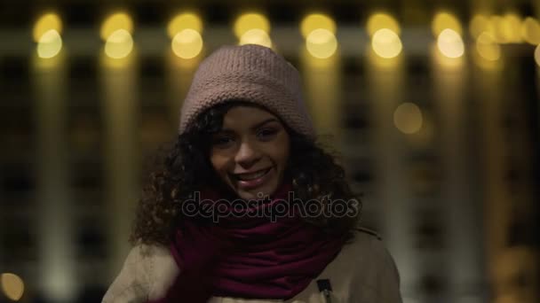 Милая двуличная девушка сердечно улыбается и машет рукой перед камерой приветствуя всех — стоковое видео