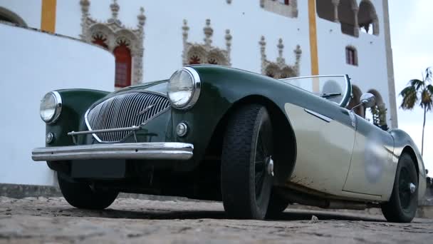 Old-fashioned roofless car parked front of white building with beautiful windows — Stock Video