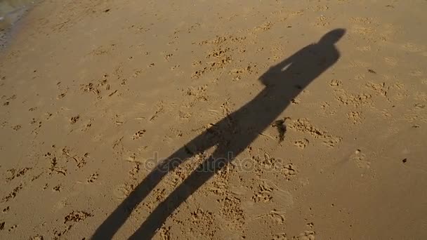 Homem feliz dançando dança engraçada na praia com sua sombra fundida na areia, bom humor — Vídeo de Stock
