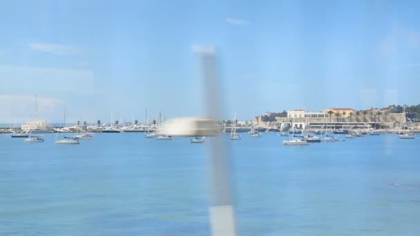Beau port d'eau bleue avec des voiliers amarrés, vue du train en mouvement — Video