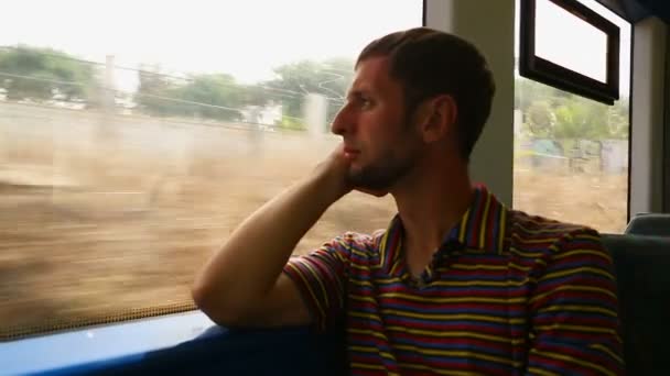 Чоловік сидить біля вікна і дивиться на зміну пейзажу з швидкого руху поїзда — стокове відео