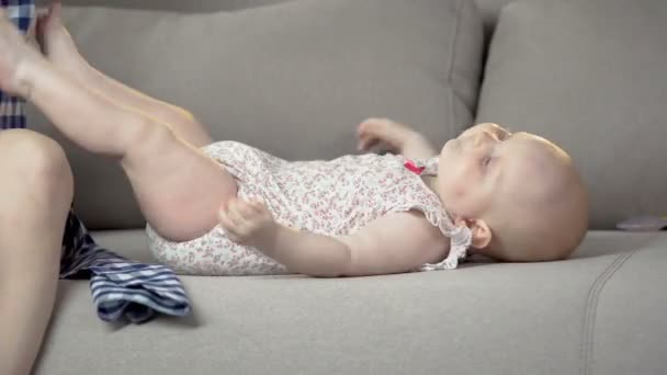 Играющая симпатичная девочка, веселящаяся с родителями дома в удобных памперсах — стоковое видео