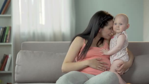 Adorable sweet baby girl hugging her pregnant mommy, love and care in family — Stock Video