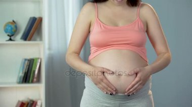 Hamile kadının büyük göbek ellerde işaretiyle şekil, Bebek için seviyorum kalp yapma