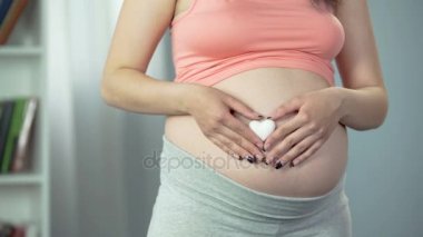 Kalp şeklinde Hatıra mutlu anne sevgisi için bebek tutan hamile kadın