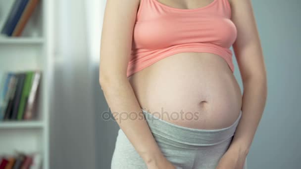 Senhora grávida esperando menina, segurando sapatos rosa perto da barriga, chá de bebê — Vídeo de Stock