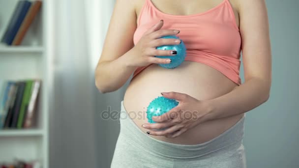 Женщина массирует свой беременный живот резиновыми шариками, чтобы расслабиться и снять стресс — стоковое видео