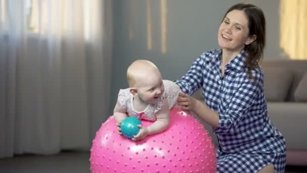 Vrolijke moeder spelen met baby, waardoor baby fitness oefeningen op grote bal — Stockvideo