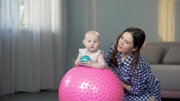 Madre feliz y linda niña sonriendo a la cámara, jugando con bolas en casa — Vídeos de Stock