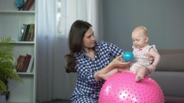 Actieve grappige babymeisje speelt met de bal, vroege ontwikkeling van de zuigeling thuis — Stockvideo