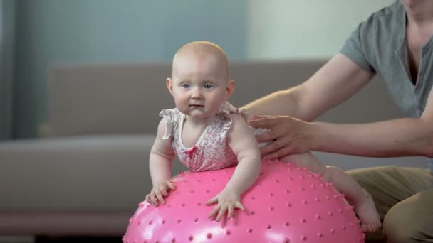 Père prudent faisant des exercices de remise en forme sur une grosse balle avec une jolie petite fille bébé — Video