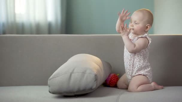 Ενεργό κοριτσάκι παλαμάκια και παίζοντας στον καναπέ στο σπίτι, χαρούμενη παιδική ηλικία — Αρχείο Βίντεο