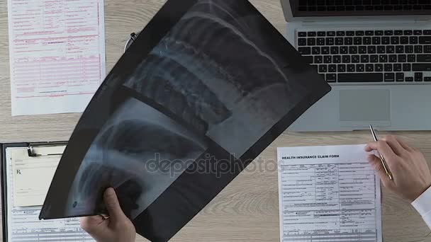 Pulmonólogo examinando cuidadosamente a los pacientes radiografía pulmonar, observando áreas sospechosas — Vídeo de stock