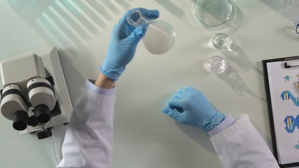 Βοηθός αρσενικό εργαστηρίου ανάμιξη υγρών αντιδραστηρίων, παρακολούθηση χημική αντίδραση — Αρχείο Βίντεο
