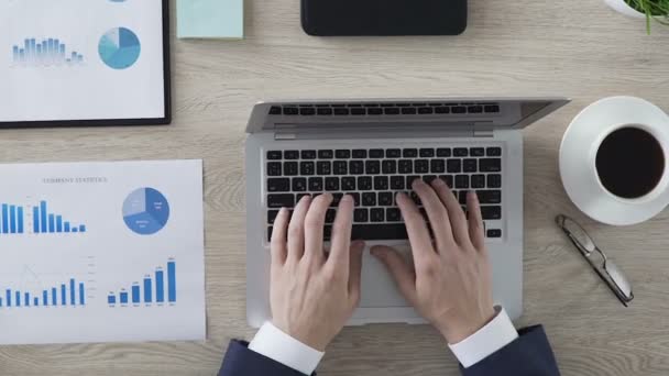 Hombre escribiendo en el ordenador portátil en el escritorio de la oficina, estadísticas y análisis de la empresa, espacio de trabajo — Vídeos de Stock