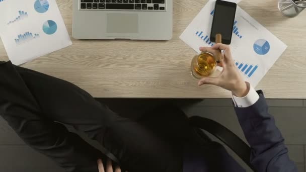 Pleased man in suit drinking cognac and smoking cigar at workplace, success — Stock Video