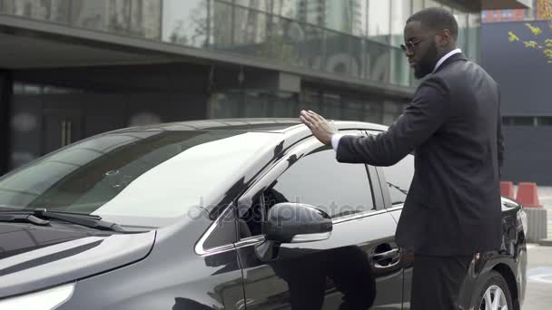 Escrupuloso hombre afroamericano limpiando su coche nuevo antes de salir del estacionamiento — Vídeo de stock