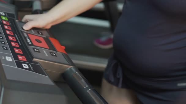 Obézní žena chůze na běžeckém pásu, nastavením rychlost na panelu, cvičení — Stock video