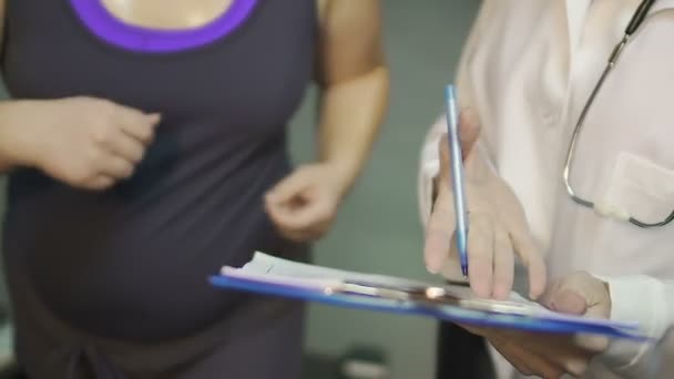 看護師医療のトレッドミルで実行されている脂肪質の女の子に紙の上のテスト結果を示す — ストック動画