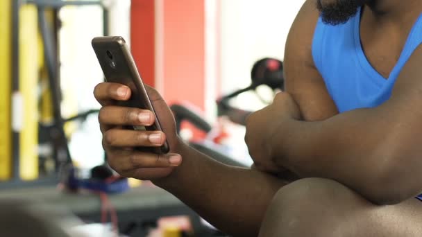 Homme métis utilisant le téléphone portable dans la salle de gym, les réseaux sociaux et la communication — Video