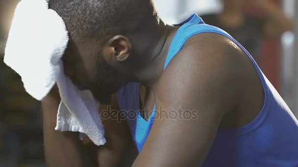 Afroamericano limpiándose la cara con toalla en el gimnasio, agotado después del entrenamiento — Vídeos de Stock