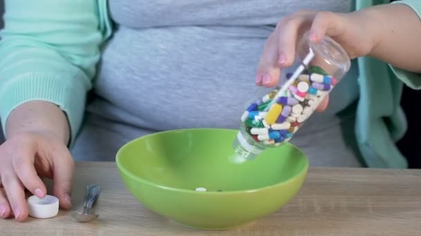 Mujer tomando frasco con pastillas para ponerlas en tazón, tomando cuchara para comer pastillas — Vídeos de Stock