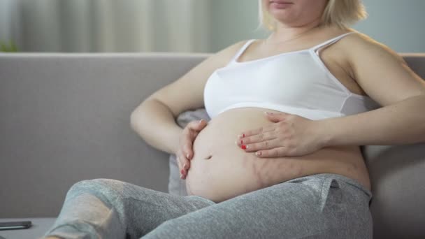 Dame streichelt sanft ihren Schwangerschaftsbauch mit Baby drinnen, gibt Liebe, Familie — Stockvideo