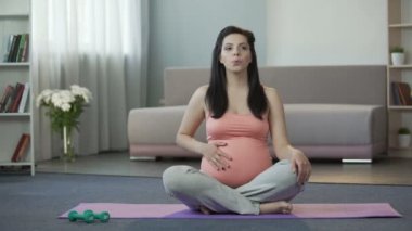 Oryantal masaj ve nefes alma egzersizleri yaparak yoga mat oturan hamile kadın
