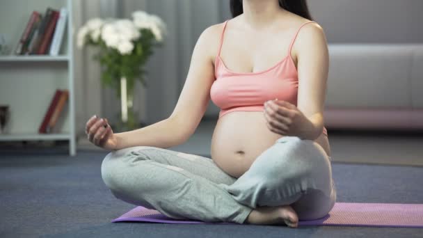 Schwangere Frau praktiziert Yoga zu Hause, beruhigt sich und ihr zukünftiges Baby — Stockvideo