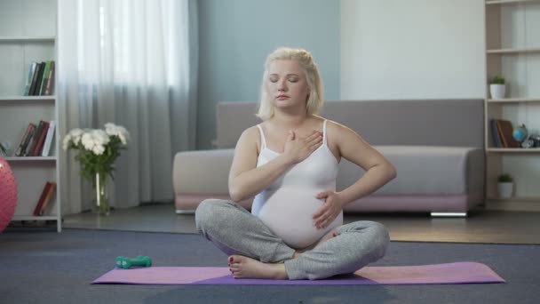 Спокойная беременная женщина слушает ощущения и прикасается к ребенку в животе — стоковое видео