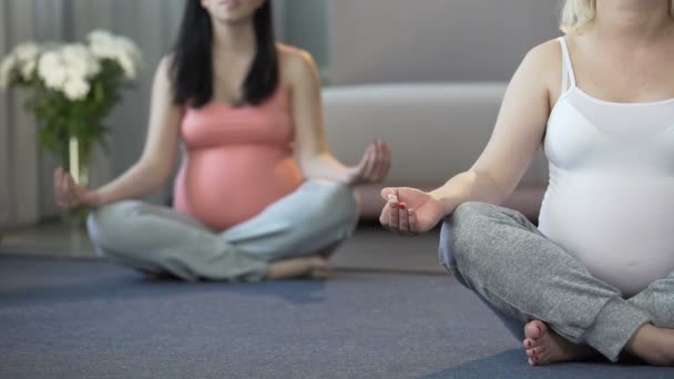 Dwóch robi ćwiczenia jogi kobiet w ciąży, aby się zrelaksować i uspokoić się w domu — Wideo stockowe