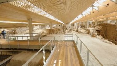 Ahşap geçit üzerinde yürüme ve Santorini üzerinde Akrotiri kalıntıları ile ilgilenen kişi